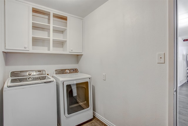 laundry area featuring dark wood-style floors, independent washer and dryer, cabinet space, and baseboards