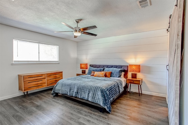 bedroom with dark wood-style floors, visible vents, a textured ceiling, and baseboards