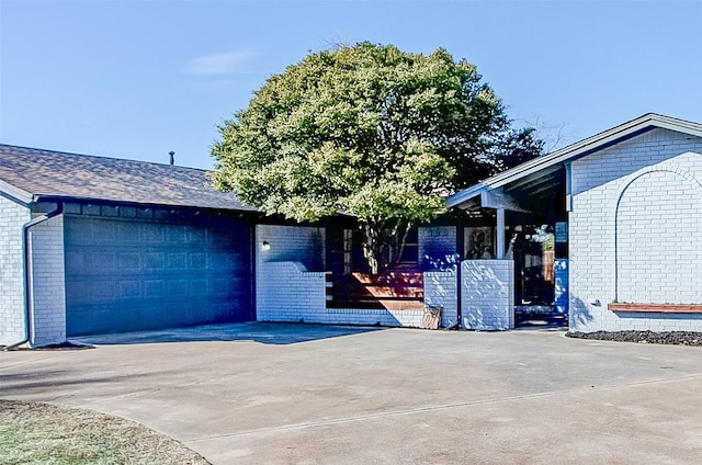 view of front of home with driveway, brick siding, roof with shingles, and an attached garage