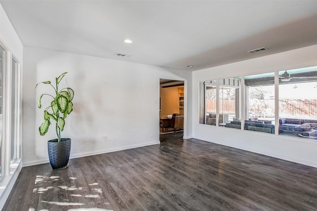 empty room featuring baseboards, visible vents, dark wood-type flooring, and recessed lighting