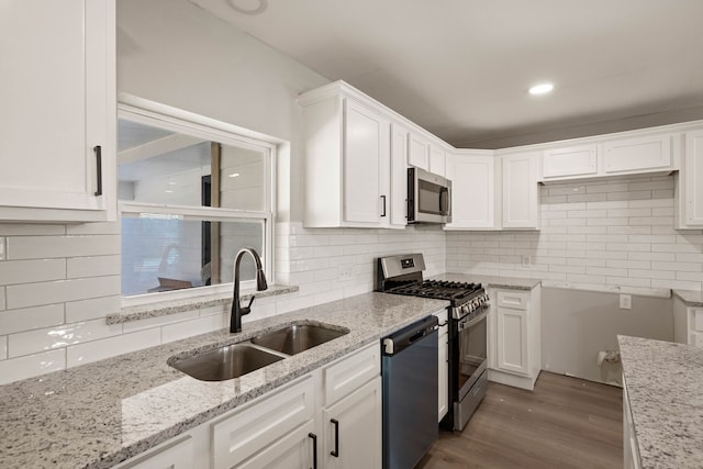 3721 Stuart Dr, Fort Worth, TX 76110 - kitchen featuring light stone counters, wood finished floors, a sink, white cabinetry, and appliances with stainless steel finishes