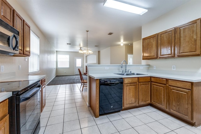 kitchen with brown cabinetry, a peninsula, light countertops, black appliances, and a sink