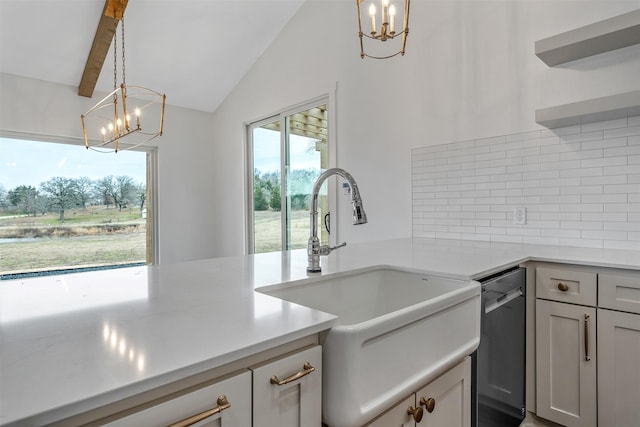 kitchen featuring decorative light fixtures, a notable chandelier, light countertops, stainless steel dishwasher, and a sink