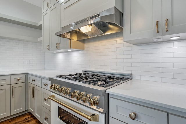 kitchen featuring under cabinet range hood, dark wood-type flooring, high end stainless steel range, decorative backsplash, and open shelves