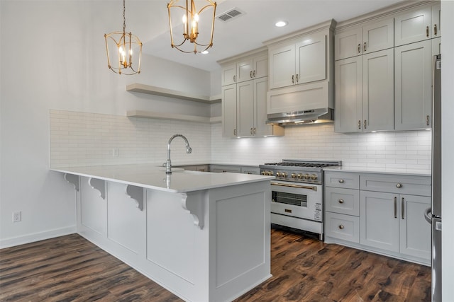 kitchen featuring range with gas stovetop, open shelves, light countertops, a peninsula, and a kitchen bar