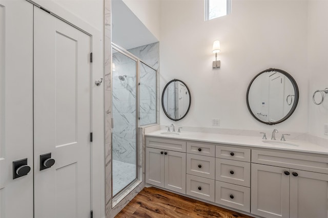 bathroom with a sink, a marble finish shower, and wood finished floors