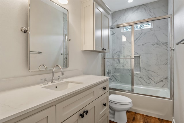 full bathroom with toilet, shower / bath combination with glass door, wood finished floors, and vanity