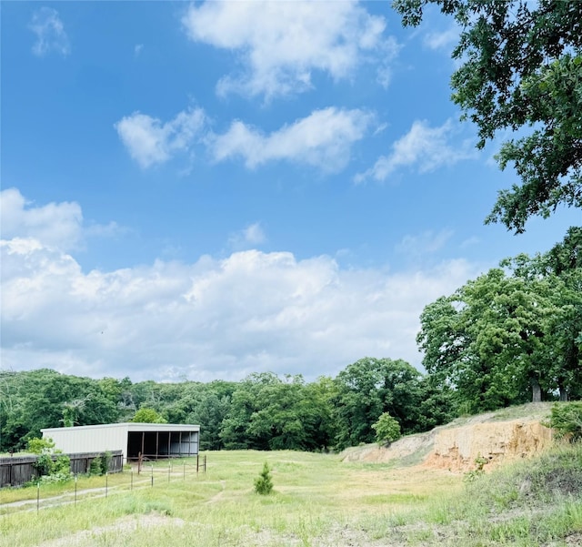 view of yard featuring a pole building, a rural view, an outdoor structure, and fence