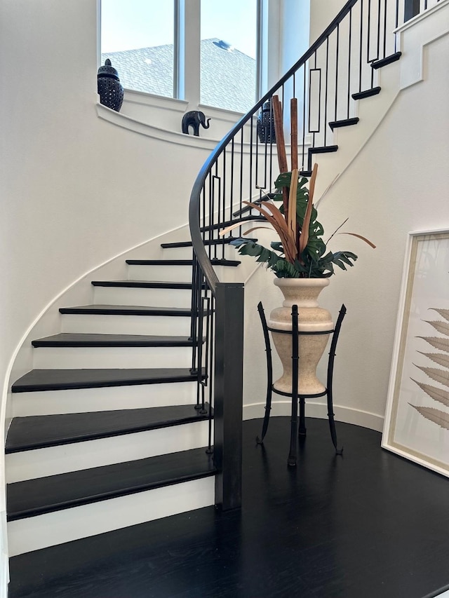 stairway with a high ceiling, baseboards, and wood finished floors