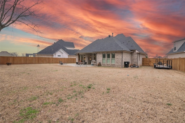 rear view of house featuring brick siding, a patio area, and a fenced backyard