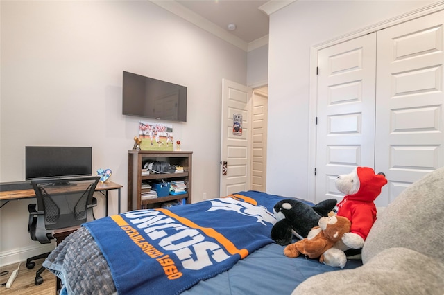 bedroom with ornamental molding, a closet, wood finished floors, and baseboards