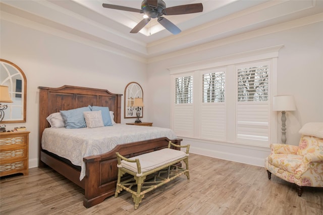 bedroom featuring baseboards, a tray ceiling, and light wood-style floors