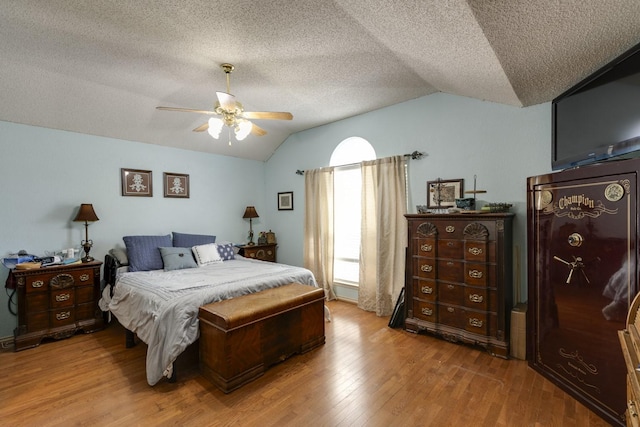 bedroom with a textured ceiling, a ceiling fan, vaulted ceiling, and wood finished floors