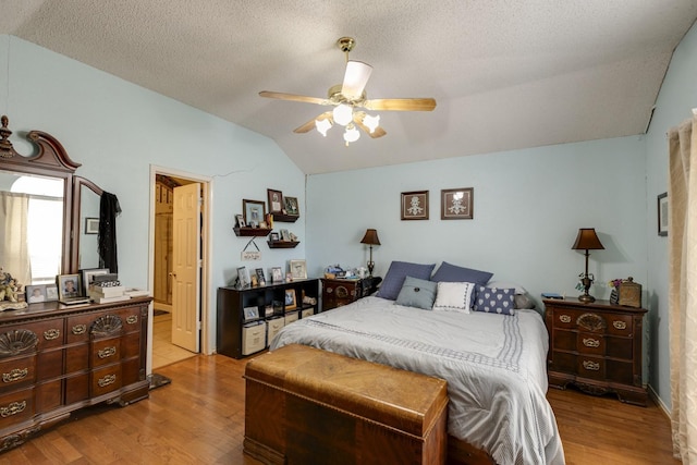 bedroom with vaulted ceiling, ceiling fan, a textured ceiling, and light wood-type flooring