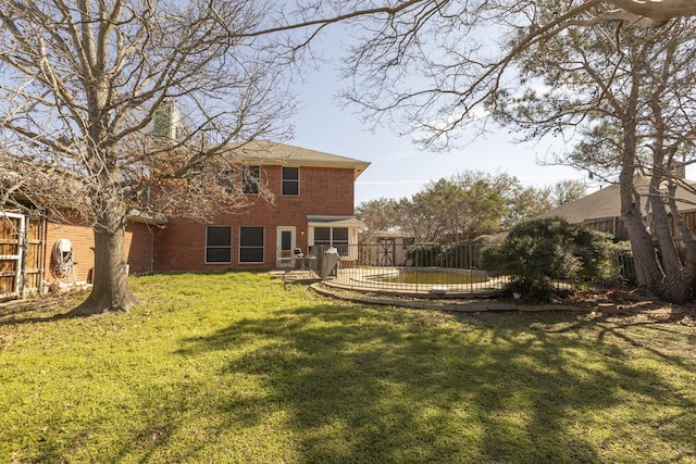 back of property with brick siding, a yard, and fence