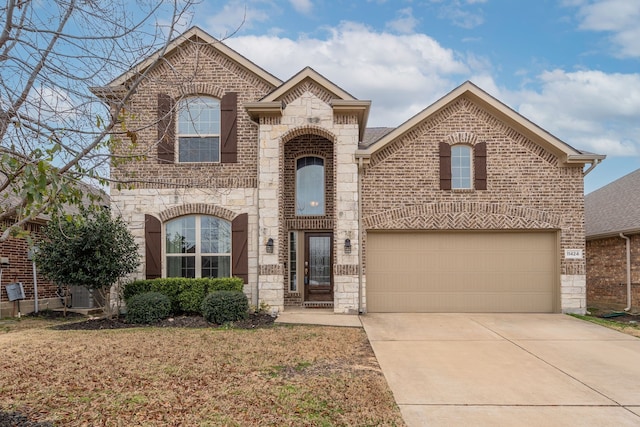 french country style house with stone siding, concrete driveway, brick siding, and a garage