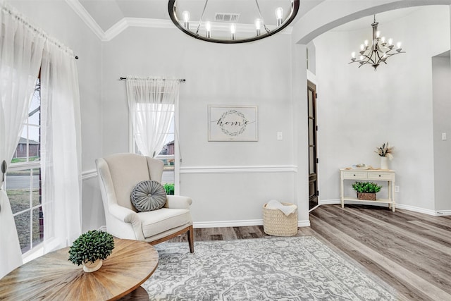 sitting room with crown molding, a healthy amount of sunlight, wood finished floors, and a notable chandelier