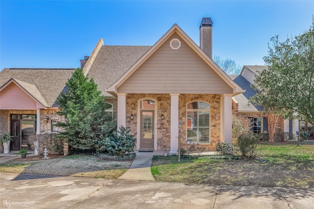 view of front of property featuring covered porch, a shingled roof, a chimney, and a front lawn