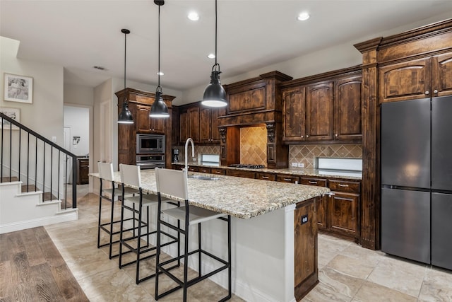 8 Center Ct, Heath, TX 75032 - kitchen with stainless steel appliances, a kitchen island with sink, a breakfast bar area, backsplash, and dark brown cabinets