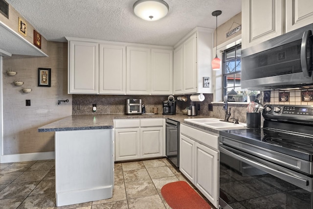 kitchen featuring white cabinets, dark countertops, appliances with stainless steel finishes, hanging light fixtures, and a textured ceiling