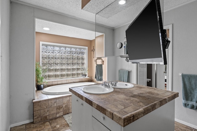 bathroom featuring a garden tub, baseboards, a textured ceiling, and vanity