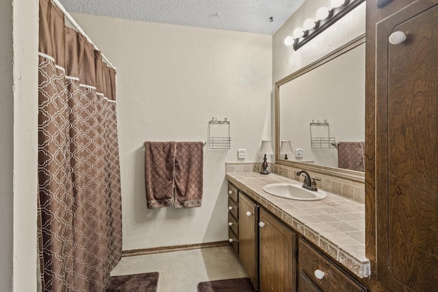 bathroom featuring a shower with curtain, baseboards, vanity, and a textured ceiling