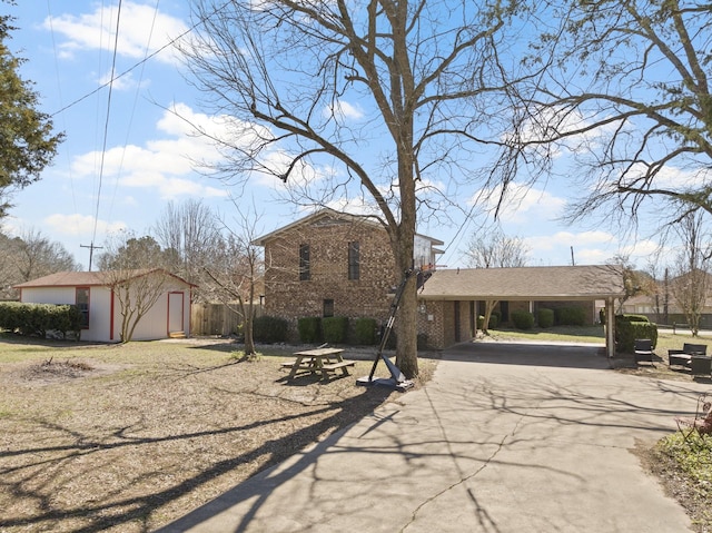 view of front of property with brick siding, driveway, and an outdoor structure