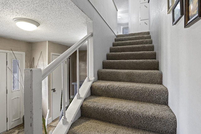 stairs featuring a textured ceiling