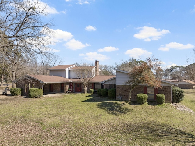 view of front facade with a garage, a chimney, a front lawn, and brick siding