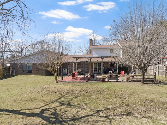 rear view of property with brick siding, a yard, a patio, a chimney, and fence