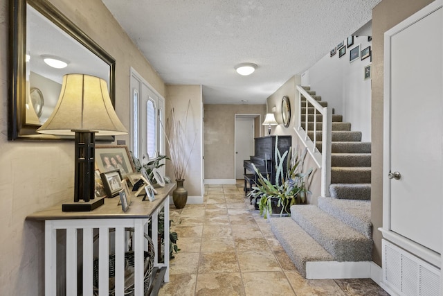 foyer entrance with stairs, a textured ceiling, and baseboards