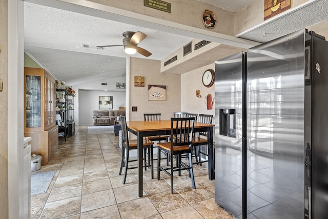 dining space featuring lofted ceiling, ceiling fan, a textured ceiling, light tile patterned flooring, and visible vents