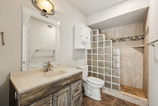 bathroom featuring tile patterned flooring, toilet, visible vents, vanity, and walk in shower