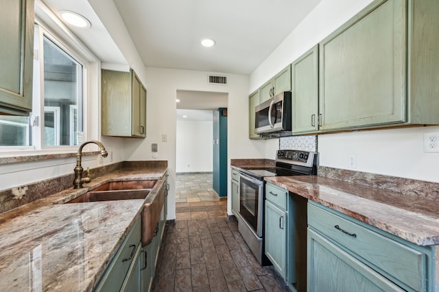 kitchen featuring stainless steel appliances, visible vents, light stone counters, and green cabinets