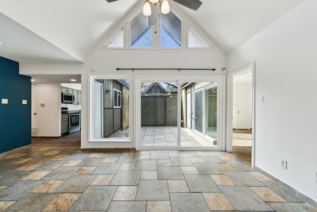 unfurnished room with high vaulted ceiling, stone finish flooring, baseboards, and a ceiling fan