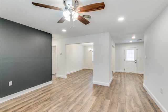 spare room featuring recessed lighting, visible vents, light wood-style floors, baseboards, and ceiling fan with notable chandelier