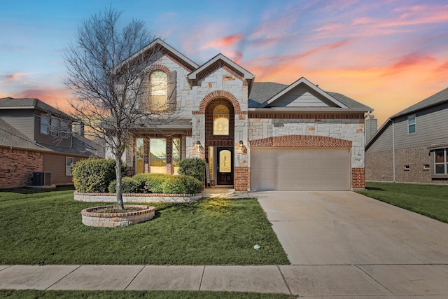 french country inspired facade featuring central AC unit, concrete driveway, stone siding, an attached garage, and brick siding