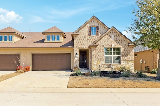 view of front of house with a garage, concrete driveway, stone siding, roof with shingles, and stucco siding