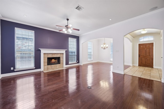 unfurnished living room featuring a tile fireplace, wood finished floors, visible vents, baseboards, and crown molding