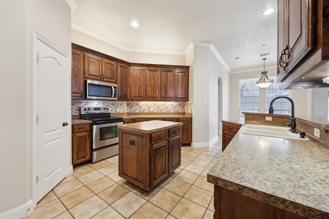 kitchen with arched walkways, a sink, appliances with stainless steel finishes, a center island, and tasteful backsplash