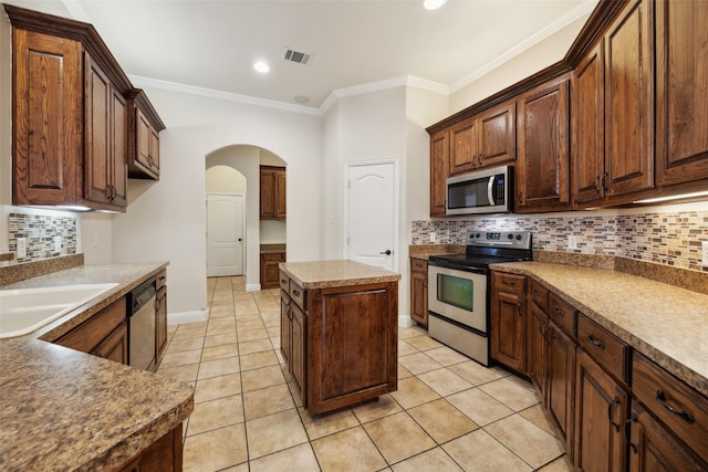 kitchen with a center island, crown molding, visible vents, appliances with stainless steel finishes, and light tile patterned flooring