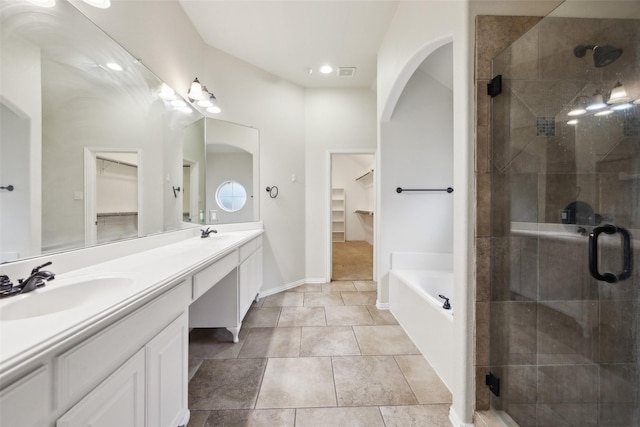 bathroom with a garden tub, double vanity, a spacious closet, a stall shower, and a sink