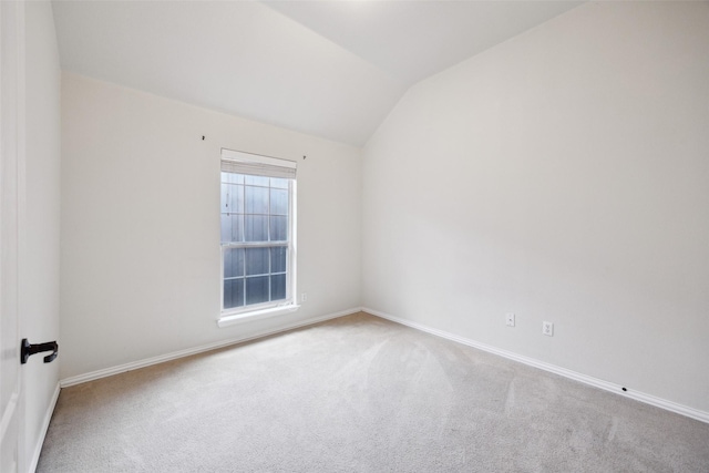 carpeted empty room with baseboards and vaulted ceiling