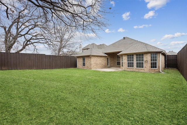 back of house featuring a patio, a fenced backyard, brick siding, a shingled roof, and a lawn