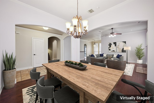 dining room with arched walkways, ornamental molding, dark wood-style floors, and visible vents