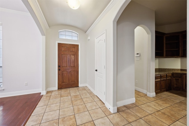 foyer featuring arched walkways, baseboards, and light tile patterned floors