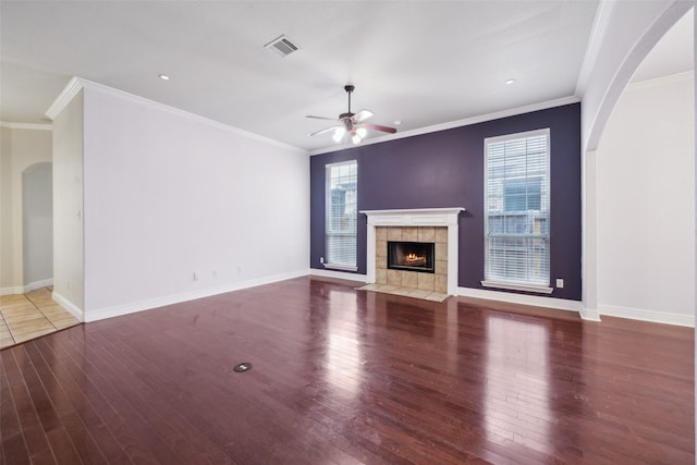 unfurnished living room featuring wood finished floors, a tile fireplace, visible vents, and baseboards