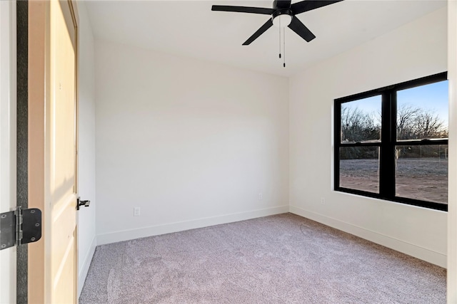 carpeted empty room featuring a ceiling fan and baseboards