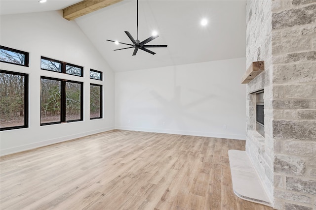 unfurnished living room with a large fireplace, light wood finished floors, baseboards, beamed ceiling, and high vaulted ceiling