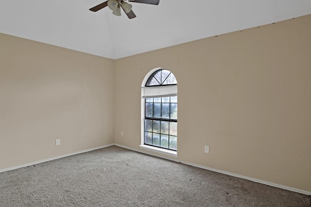 carpeted empty room with vaulted ceiling, baseboards, and ceiling fan